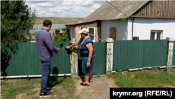 Жителька Афанасіївки Валентина Понуренко показує рівень затоплення 2023-го після підриву дамби Каховської ГЕС. Липень 2026 року