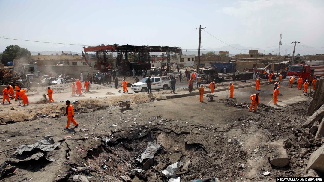 Civili care inspectează locul unde a fost distrusă benzinăria, în urma atacului cu bombă de la Kabul, din Zona Verde