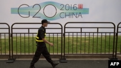 G20 саммиті өтетін Ханчжоу қаласында қонақүй жанынан өтіп бара жатқан қауіпсіздік қызметкері. Қытай, 2 қыркүйек 2016 жыл.