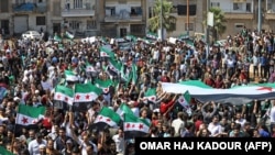 Syrian protesters wave their national flag as they demonstrate against the regime and its ally Russia in the rebel-held city of Idlib on September 7.