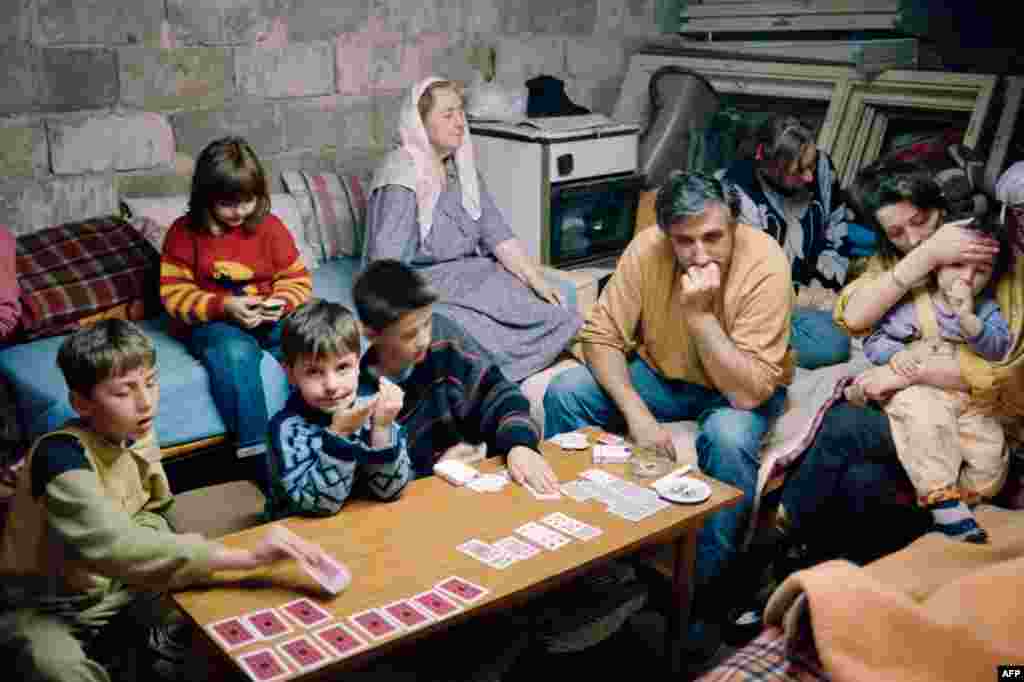 A family takes shelter in a cellar in Sarajevo on June 6, 1992, as shells fall on the Bosnian capital. The fighting continued, despite a UN-brokered deal to reopen the airport and for Serbian troops to withdraw from their barracks in the center of the city.&nbsp;