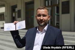 Сяргей Чэрачань паказвае журналістам пасьведчаньне кандыдата ў прэзідэнты