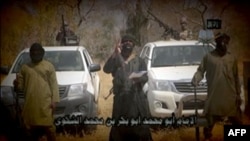 «Боко Харам» басшысы Әбубакар Шекаудың (ортада) 2015 жылғы ақпандағы видео-үндеуінен скриншот.