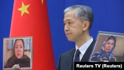 Chinese Foreign Ministry spokesman Wang Wenbin holds up pictures of the two women during a news conference in Beijing on February 23.