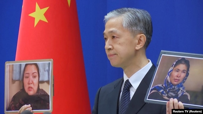 Chinese Foreign Ministry spokesman Wang Wenbin holds up pictures of the two women during a news conference in Beijing on February 23.