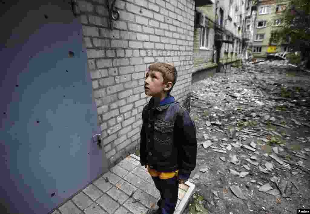 A boy looks at shrapnel holes on the door of a residential building, damaged by what locals say was overnight shelling by Ukrainian forces in the eastern town of Slovyansk on June 12. (Reuters/Gleb Garanich)