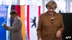 German Chancellor and Christian Democratic Union candidate Angela Merkel casts her ballot next to husband, Joachim Sauer, at a polling station in Berlin.