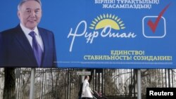 "Нұр Отан" партиясының үгіт-насихат билбордының жанында кетіп бара жатқан адамдар. Алматы, 11 наурыз 2016 жыл (Көрнекі сурет).