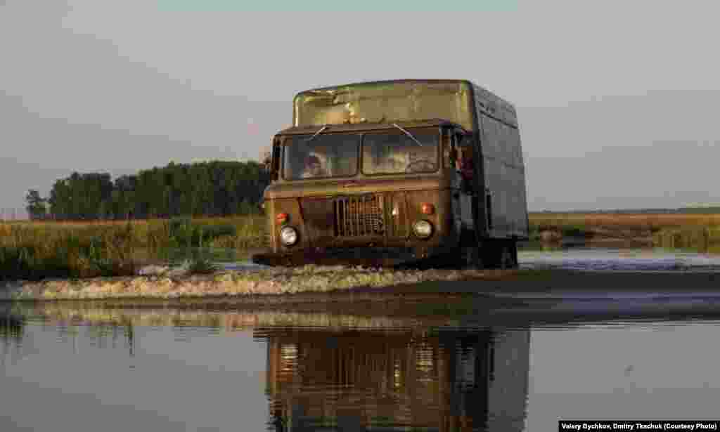 A truck wades its way through the water with a delivery.