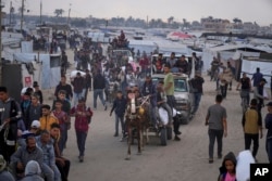 Un grup de palestinieni cară sacu cu alimente și ajutoare umanitare furnizate de Fundația Umanitară Gaza, o organizație susținută de SUA și aprobată de Israel. Khan Younis, sudul Fâșiei Gaza, marți, 3 iunie 2025.