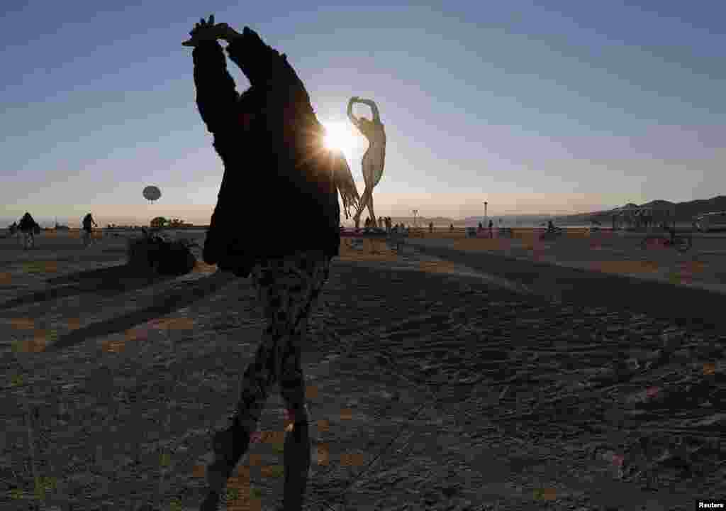 Rochelle Schieck dances near the "Truth is Beauty" sculpture, by Marco Cochrane, at the 2013 Burning Man arts and music festival in Nevada.