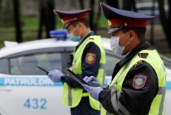Жолда жүргізушілерді тексеріп тұрған полиция қызметкерлері. Алматы, 14 сәуір 2020 жыл.
