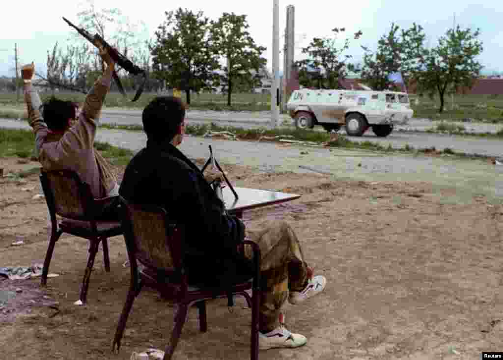 Вооруженные мужчины приветствуют проезжающую недалеко от аэропорта Сараево автомашину ООН. 14 мая 1993 года. Операция по доставке воздушным транспортом гуманитарного груза в Сараево - под названием Operation Provide Promise - продолжалась с июля 1992 года по январь 1996 года, став самой продолжительной в истории.&nbsp;