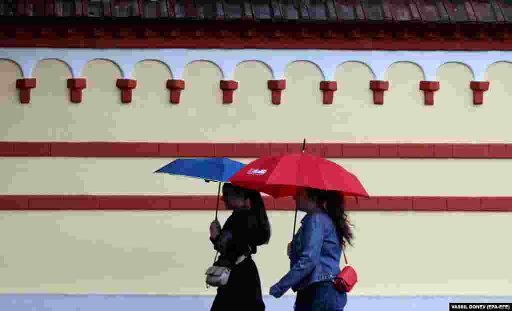 Women walk with umbrellas during a rainy autumn day in Sofia, Bulgaria.