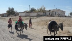 Аманкелді ауылында су тасып жүрген балалар. Оңтүстік Қазақстан облысы, Қазығұрт ауданы, Аманкелді ауылы. 21 қыркүйек, 2014 жыл. (Көрнекі сурет).