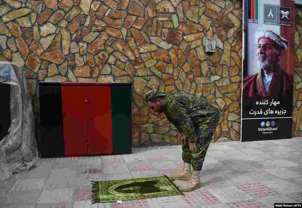 A security officer prays next to a poster of Afghan presidential candidate Ashraf Ghani at his campaign headquarters&#39; call center in Kabul during the election on September 30. (AFP/Wakil Kohsar)