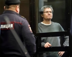 Former Economy Minister Aleksei Ulyukayev inside a glass defendants' cage in a courtroom in Moscow in April 2018