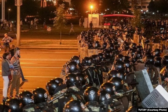 Maksim (left) confronts riot police on election night in 2020.