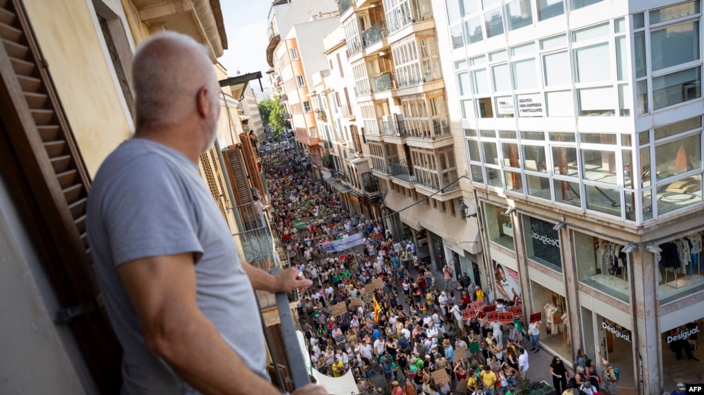 Një burrë shikon nga ballkoni i tij një protestë kundër turizmit të tepërt në Palma de Mallorca, Spanjë, 15 qershor 2025.