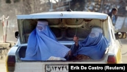 Două femei afgane călătoresc în portbagajul unei mașini din Charikar, la nord de Kabul, pe 18 februarie 2003. Burqa, ce acoperă o femeie din cap până în picioare, a devenit un simbol al opresiunii talibanilor asupra femeilor. Poză făcută la 18 februarie 2003.