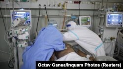 An intensive-care unit doctor and nurse assist a COVID-19 at a hospital in Bucharest. 