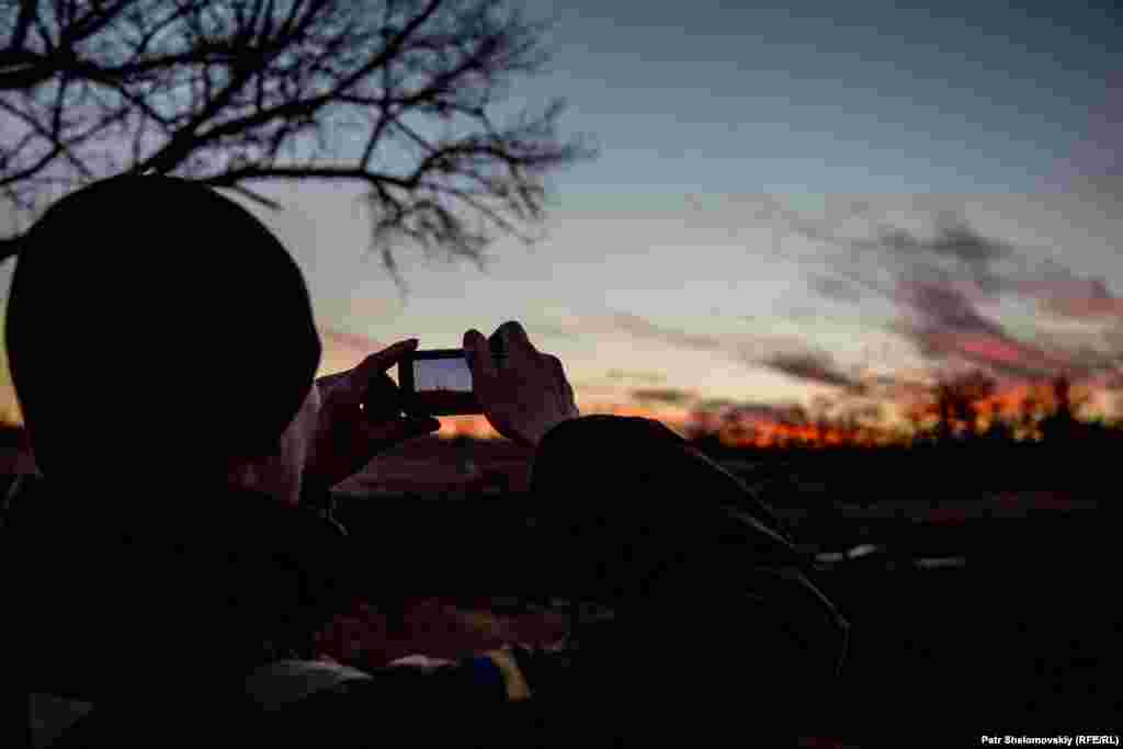 In a calm moment, a Ukrainian government serviceman takes a picture of the sunset.