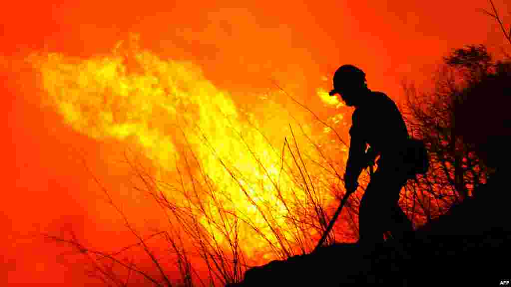 A Spanish firefighter tries to extinguish a wildfire in Ller near La Junquera on July 23. Three people were killed as winds whipped up a wildfire that raged out of control in northeastern Spain. (AFP/Lluis Gene)