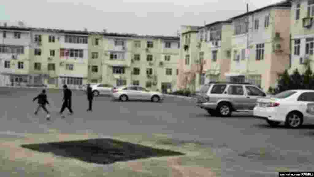 Çagalar köpgatly ýaşaýyş jaýlaryň howlusynda top oýnaýarlar, Aşgabat