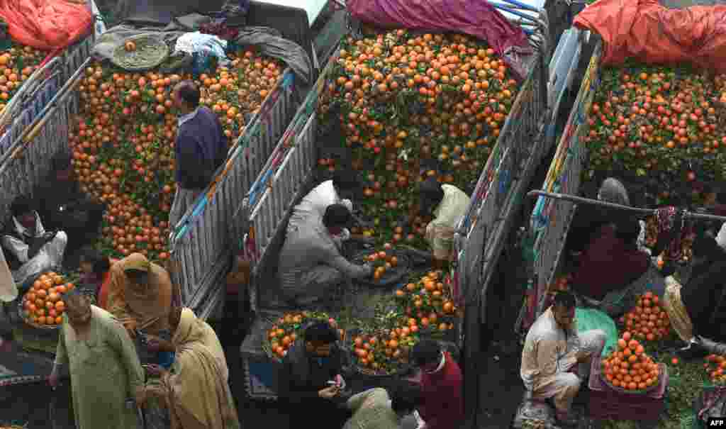 Pakistani traders sell oranges on their trucks at a fruit market in Lahore. (AFP/Arif Ali)