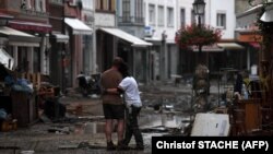 Un cuplu se uită la distrugerea lăsată în urmă de inundații pe străzile orașului Ahrweiler-Bad Neuenahr.