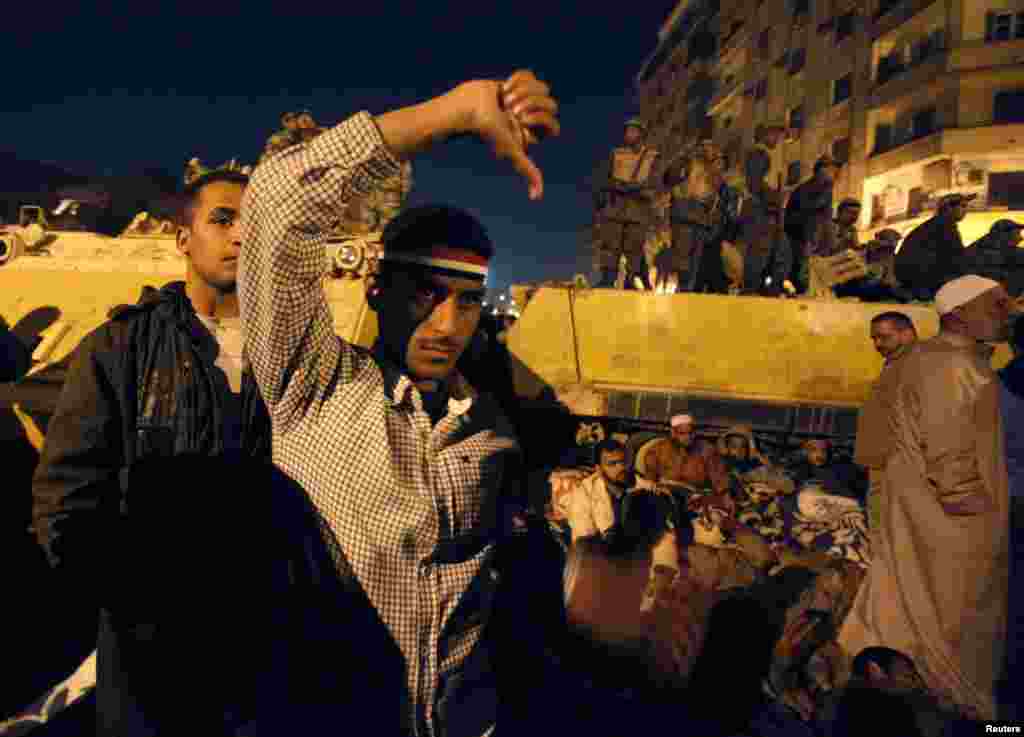 Demonstrators react as they listen to Mubarak's speech in front of a big screen in Tahrir Square on February 10, 2011.