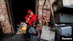 Anzila Semeul cries while sitting with her daughter in front of their home after it was lit on fire by a mob two days earlier, in Badami Bagh, Lahore, in March 2013.
