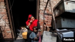 Anzila Semeul cries while sitting with her daughter in front of their home after it was lit on fire by a mob two days earlier, in Badami Bagh, Lahore, in March 2013.