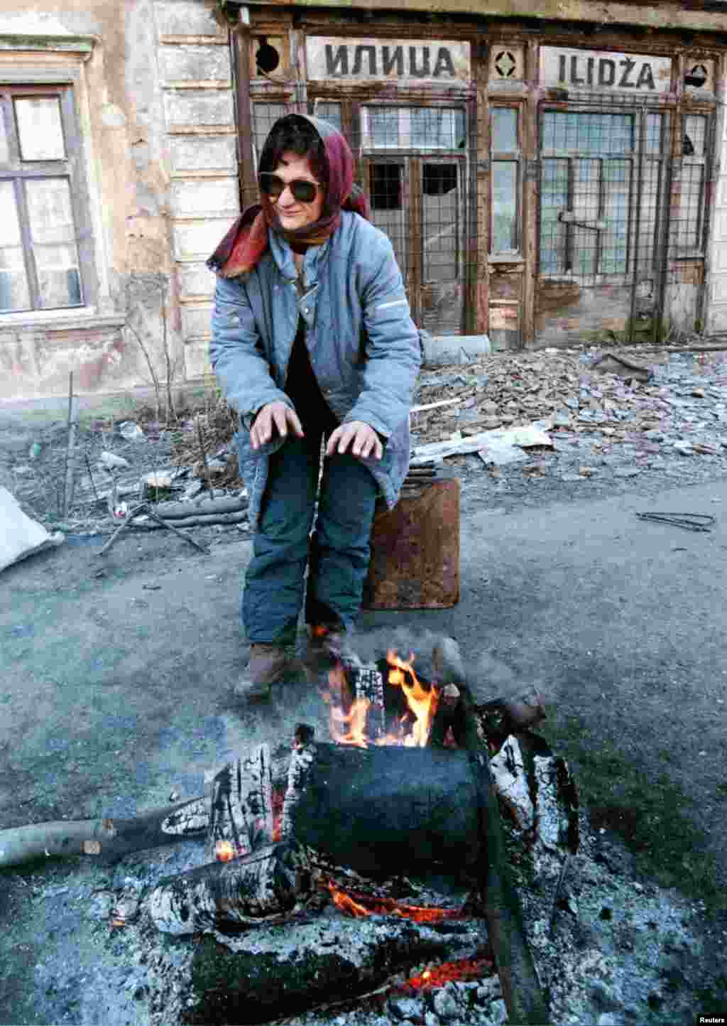 Žena se grije na ulici u centru Ilidže, naselja koje su tokom opsade grada pod kontrolom držale snage bosanskih Srba i koje je Dejtonskim sporazumom pripalo Federaciji BiH. 2. februar. 1996.