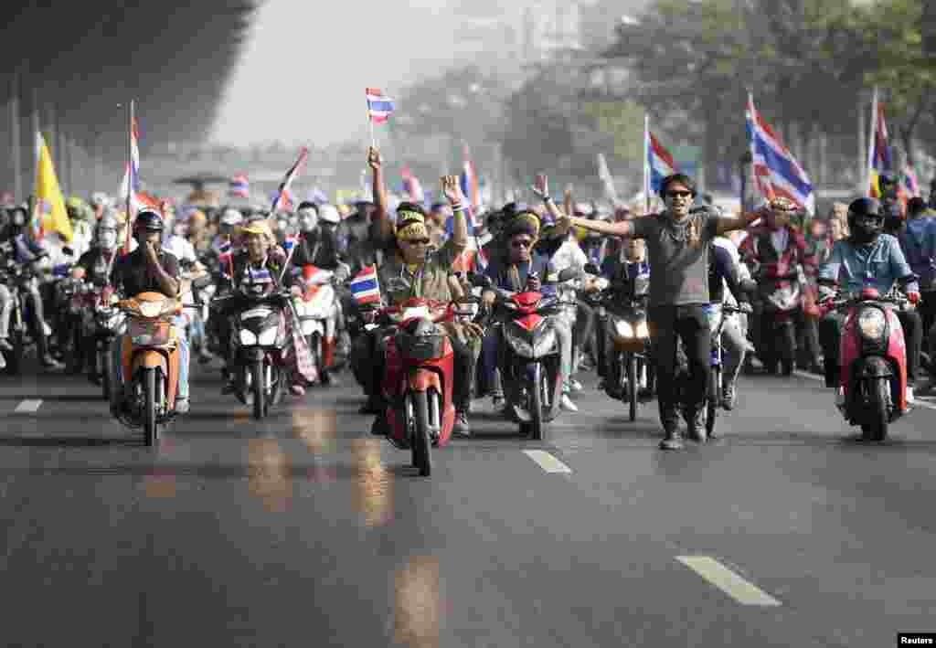 Antigovernment protesters with Thai national flags ride their motorbikes as they rally on a main road in Bangkok on December 9. (Reuters/Dylan Martinez)
