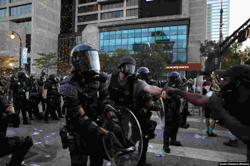 Një zyrtar policor shkëmben një përshëndetje me një protestues, teksa policia tenton të ndalojë përshkallëzimin e situatës pas protestave të lidhura me vdekjen e Floydit.