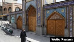 A woman wearing a protective face mask and gloves walks past the Imamzadeh Saleh shrine, amid fear of the coronavirus disease (COVID-19), in Tehran, April 2, 2020