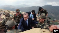Turkish Prime Minister Tayyip Erdogan (center) talks with Turkish soldiers in a trench during his visit to the Turkish city of Hakkari on the border with Iraq on June 20.