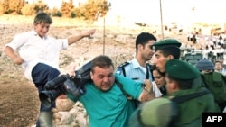 Amir al-Zsavari palesztin operatőrt zsidó telepesek és izraeli rendőrök támadják, a palesztinok és telepesek között a megosztott ciszjordániai Hebronban 2000. július 15-n kitört összecsapások idején