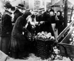 A woman selling tin cans on the streets of Berlin in 1923 amid poverty and dizzying hyperinflation.