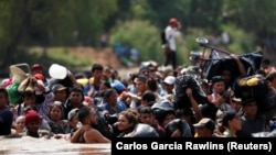 Caravana de migranți traversînd un rîu în Guatemala, 29 octobrie 2018.