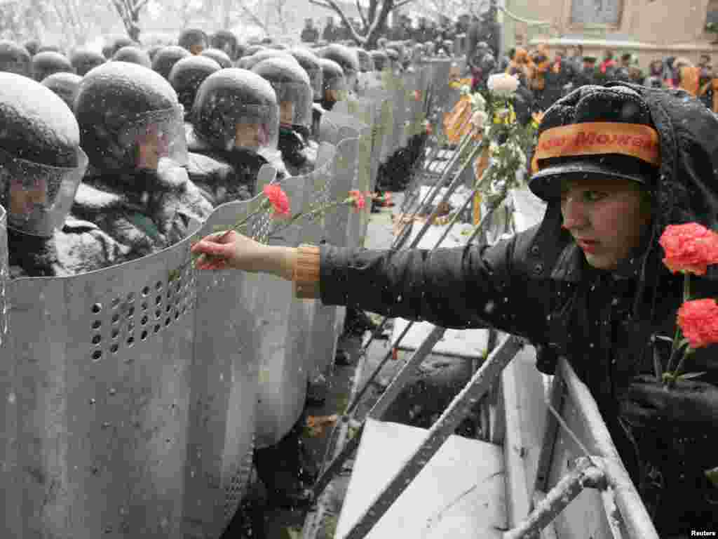 A Ukrainian woman places carnations into the shields of anti-riot policemen standing outside the presidential office in Kyiv, November 24, 2004. Ukraine's authorities raised the stakes in a face-off with their liberal opposition on Wednesday as they prepared to announce results of a disputed election that are likely to infuriate thousands of protesters in the streets. REUTERS/Vasily Fedosenko 