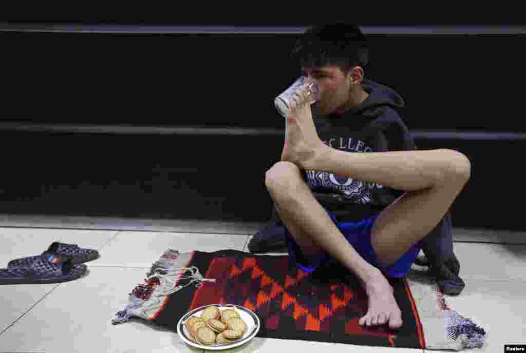 Karimi drinks milk using his foot to hold the cup.