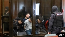 Част от 19-имата подсъдими за терористичната атака в "Крокус Сити Хол", изолирани в съдебната зала на Втори западен окръжен военен съд в Москва, 4 август 2025 г.