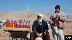 A man and his son sell fuel packed in water bottles on the outskirts of the Afghan city of Herat, near the western border with Iran, a result of the recent Iranian blockade.