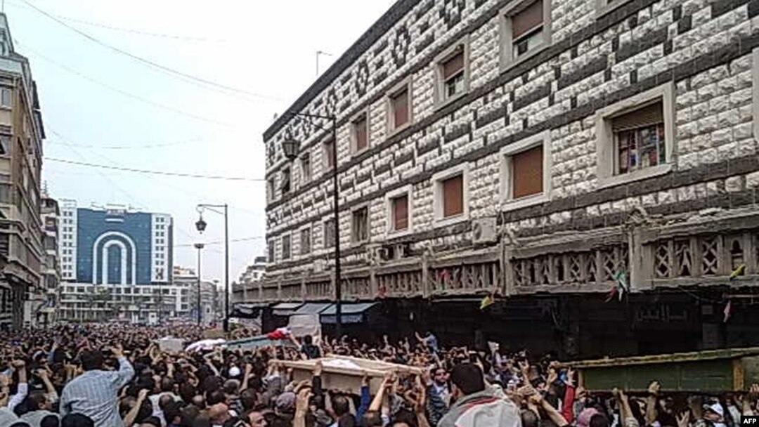 A mobile-phone image shows what AFP describes as an "alternative source" of a funeral for dead protesters in Homs on April 18.