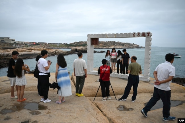 Njerëzit bëjnë foto me Ngushticën e Tajvanit në sfond në një vend turistik të quajtur "68 milje detare" në ishullin Pingtan, pika më e afërt me ishullin kryesor të Kinës, Tajvanin, në Provincën Fujian të Kinës juglindore, më 24 maj 2024.