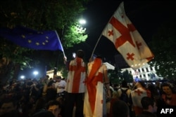 Demonstrators hold an EU and Georgian flags as they protest outside the Georgian parliament during a rally against a controversial "foreign agent" bill, which Brussels warns would undermine Georgia's European aspirations, in Tbilisi on May 1.