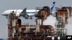 In this Thursday, Dec. 13, 2018 photo a passenger plane prepares for landing near an oil refinery in Kawasaki, southwest of Tokyo. (AP Photo/Koji Sasahara)