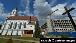 Выгляд на касьцёл Сьвятога Роха і будоўлю Акадэміі нацыянальнай бясьпекі КДБ. Фотаздымак 4 чэрвеня 2026 году.